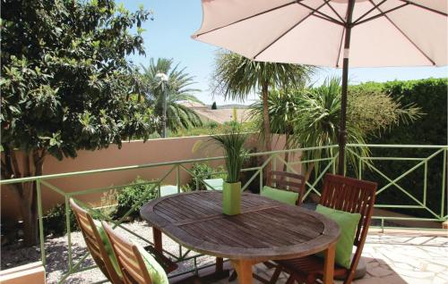 d'une table en bois avec des chaises et un parasol sur le balcon. dans l'établissement Gorgeous Home In Creissan With Wifi, à Creissan