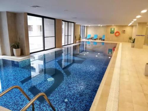 een zwembad met een blauwe vloer in een gebouw bij Luxury Studio - Damac Tower Amman in Amman