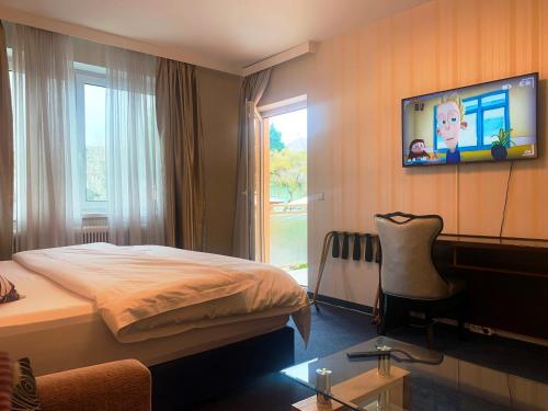 Habitación de hotel con cama y TV en la pared en Hotel Austria en Gablitz