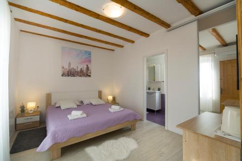a bedroom with a purple bed and a bathroom at House Braida in Bale