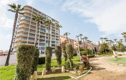 a large apartment building with palm trees and a park at Amazing Apartment In Oropesa Del Mar in Oropesa del Mar