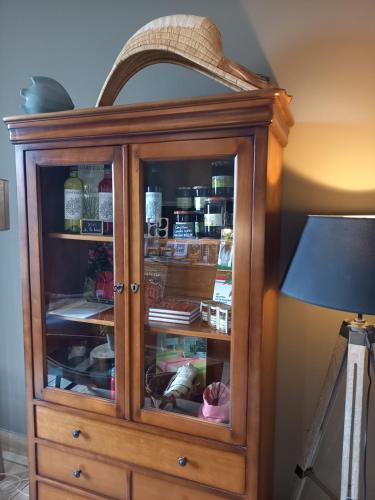 a wooden cabinet with glass doors next to a lamp at Hôtel La Caravelle in Ciboure