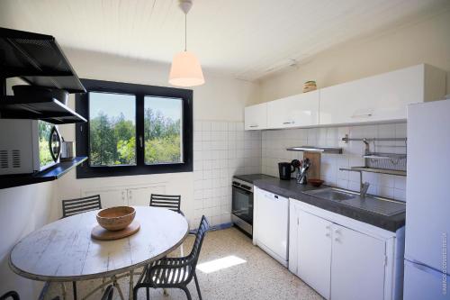 een keuken met een tafel en stoelen en een raam bij Maison dans les Arbres, SPA, Tennis, Parking in Nîmes