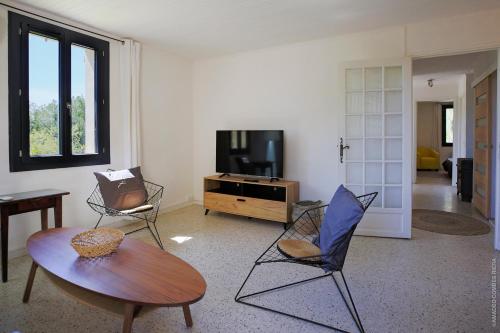 - un salon avec une table, des chaises et une télévision dans l'établissement Maison dans les Arbres, SPA, Tennis, Parking, à Nîmes