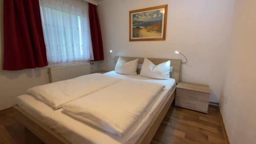 um quarto com uma cama com lençóis brancos e uma janela em Ferienanlage Mönchgut, Ferienhaus Mönchgut em Göhren