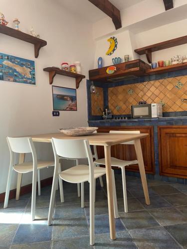 a kitchen with a wooden table and white chairs at Le case di Nunzia in Lampedusa