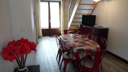 a dining room with a table and chairs with red flowers at LES GITES D'AVEZE Volcan, Sancy, Bourboule in Avèze