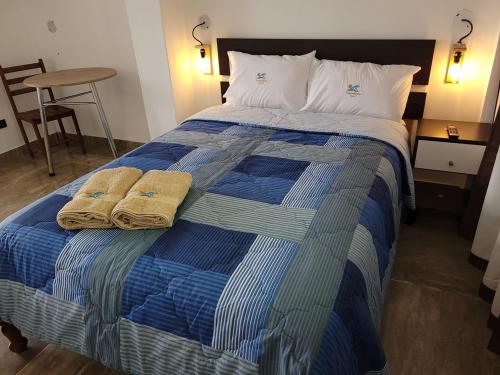 Una cama azul y blanca con dos toallas. en TUPANANCHIKAMA, en Puerto Chicama
