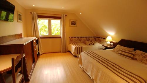 a hotel room with two beds and a window at Hotel Azaleia in Gramado