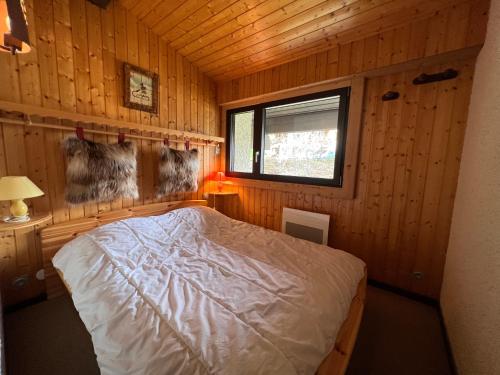 une chambre avec un lit dans une cabane en bois dans l'établissement Sapaudia G - Appartement skis aux pieds, belle vue, à La Clusaz