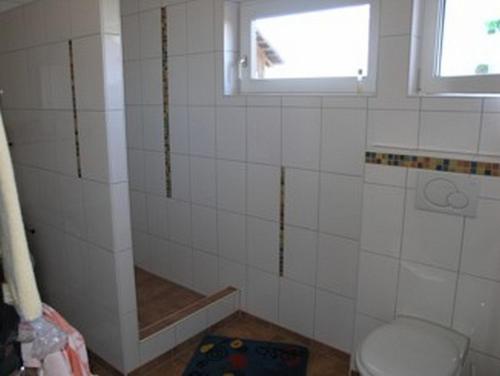 baño de azulejos blancos con aseo y ventana en Ferienwohnung Nr 2, neben Bauernhof, Roßhaupten, Allgäu, en Rosshaupten