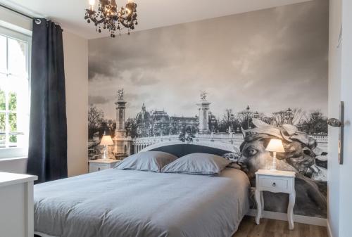 - une chambre avec un grand lit orné d'une peinture murale dans l'établissement voyageurs, à Valognes