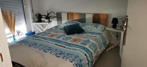 een bed met een blauw en wit dekbed en een raam bij Bulle Marine in Calais