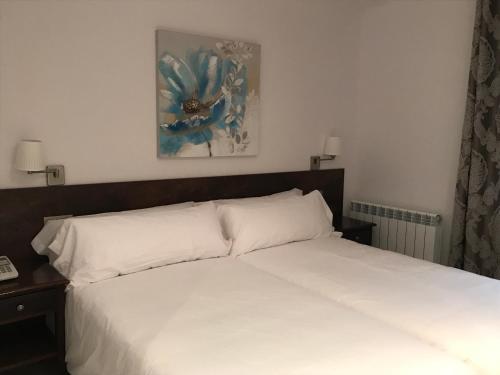 a bedroom with a white bed and a picture on the wall at Aston Hotel in Andorra la Vella