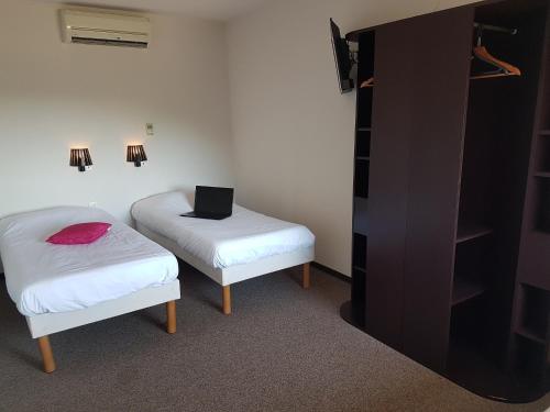 a room with two beds and a laptop on a table at Enzo Hotels Quimperle in Quimperlé