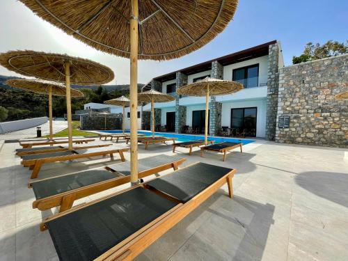 a group of benches with umbrellas in front of a building at Terra Pietra Luxury Villas & Suites in Lardos