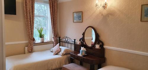 a bedroom with two beds and a mirror and a window at The Limes in Stow on the Wold