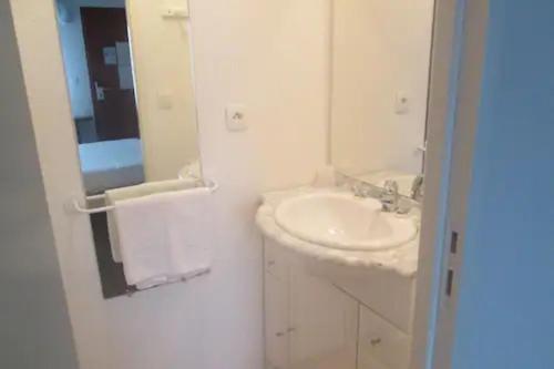 a white bathroom with a sink and a mirror at Enzo Hotels Quimperle in Quimperlé