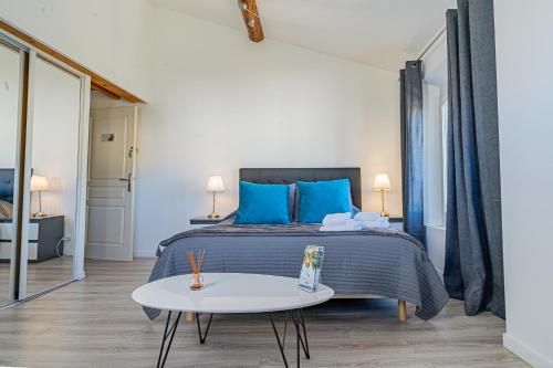 a bedroom with a bed with blue pillows and a table at Domaine de l'Aufrene in Hyères