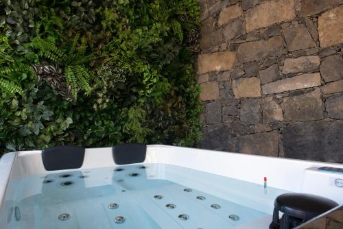 a bath tub in front of a stone wall at Furnas Sweet Home in Furnas