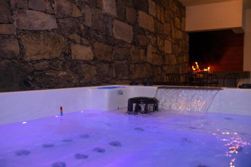 a jacuzzi tub with a stone wall at Furnas Sweet Home in Furnas