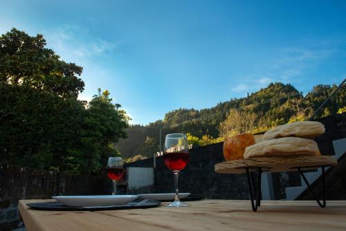 a table with two glasses of red wine and bread at Furnas Sweet Home in Furnas