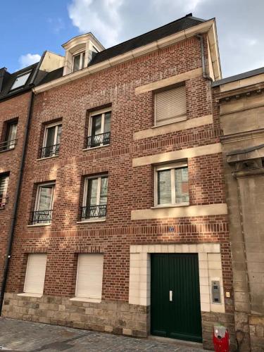 um edifício de tijolos vermelhos com uma porta verde em Studio Taormina Valenciennes Centre em Valenciennes