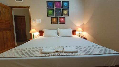 a bedroom with a large white bed with pictures on the wall at OmBodhi Retreat in Kumta