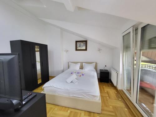 a bedroom with a white bed and a tv at Mega Mall Monza Super Spa in Bucharest