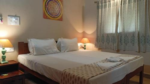 a bedroom with a large white bed with two lamps at OmBodhi Retreat in Kumta