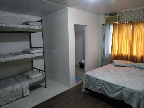 a bedroom with two bunk beds and a window at Pousada Max House entre Praias de SFS in São Francisco do Sul