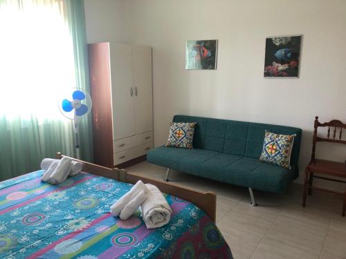 a bedroom with a bed and a green couch at Sirenetta in Torre Suda