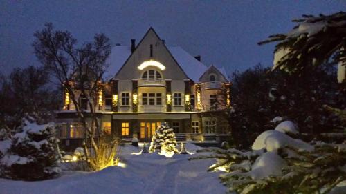 une grande maison avec des lumières de Noël dans la neige dans l'établissement Willa Granit, à Krościenko nad Dunajcem