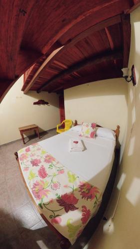 a bedroom with a bed with a floral bedspread at La Casa de las Flores Hostal in Jardin
