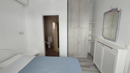 a white bedroom with a bed and a mirror at Anemomylos Houses in Koufonisia