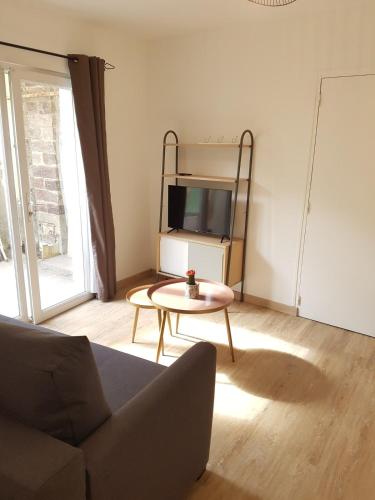 un salon avec un canapé, une table et une télévision dans l'établissement Joli duplex calme avec terrasse centre Paimpol, à Paimpol