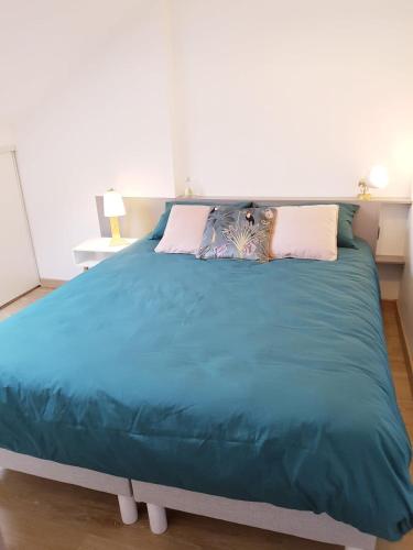 un grand lit avec une couette bleue dans une chambre dans l'établissement Joli duplex calme avec terrasse centre Paimpol, à Paimpol