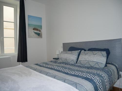 - un lit avec des oreillers bleus et blancs et une fenêtre dans l'établissement George V - Admiral's delightful sea view, à La Chaume