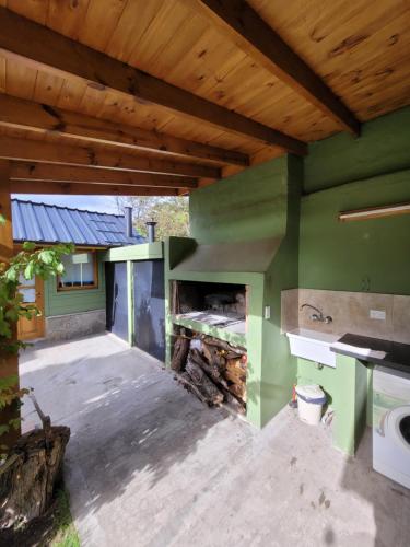 an outdoor kitchen with green walls and a fireplace at Cabaña Honey in San Martín de los Andes