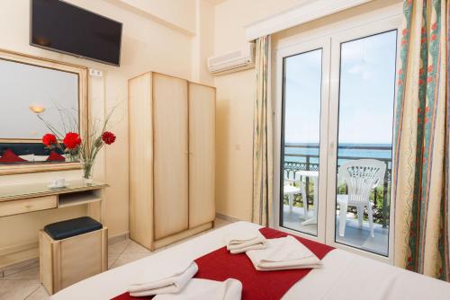 a hotel room with a bed and a large window at Fedra Hotel in Chrysi Ammoudia