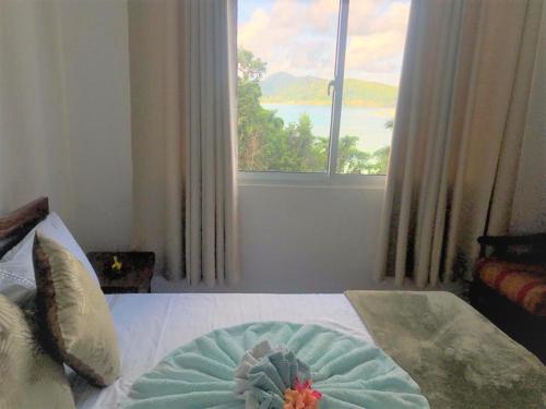 a bedroom with a bed with a large window at Seychelles Yellow Petals in Anse Boileau
