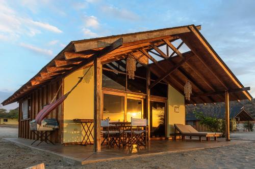 a pavilion with a table and chairs in front of a building at Wallac Bungalows Canoas de Punta Sal in Canoas De Punta Sal