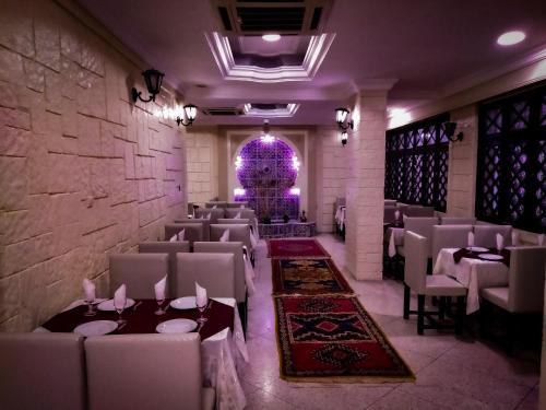 a dining room with chairs and tables and a stone wall at Hotel Tiout in Taroudant
