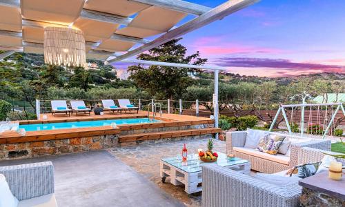 een patio met een zwembad en stoelen en een tafel bij Cretan Lodge Heated Pool in Agios Nikolaos