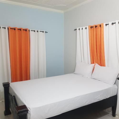 a bed with orange and white curtains in a room at The Braemar Suite III New Kingston in Kingston