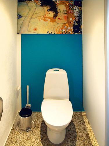 a bathroom with a white toilet in a blue wall at Guldborg Camping & Cottages - Famillyspace in Guldborg