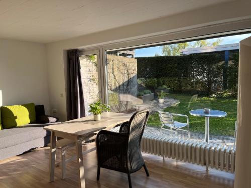 ein Wohnzimmer mit einem Tisch und Stühlen sowie einem großen Fenster in der Unterkunft Ferienwohnung Am Sultmer mit Terrasse und Garten in Northeim