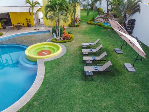 una vista aérea de una piscina con sillas y sombrillas en Hotel Magico Inn, en Cuautla Morelos