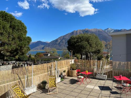 a patio with tables and chairs with mountains in the background at Appartamento con terrazza a due minuti dal lago in Minusio