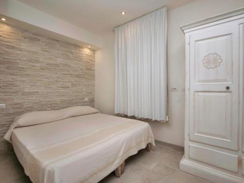 a bedroom with a bed and a brick wall at Iside Accommodations in Olbia